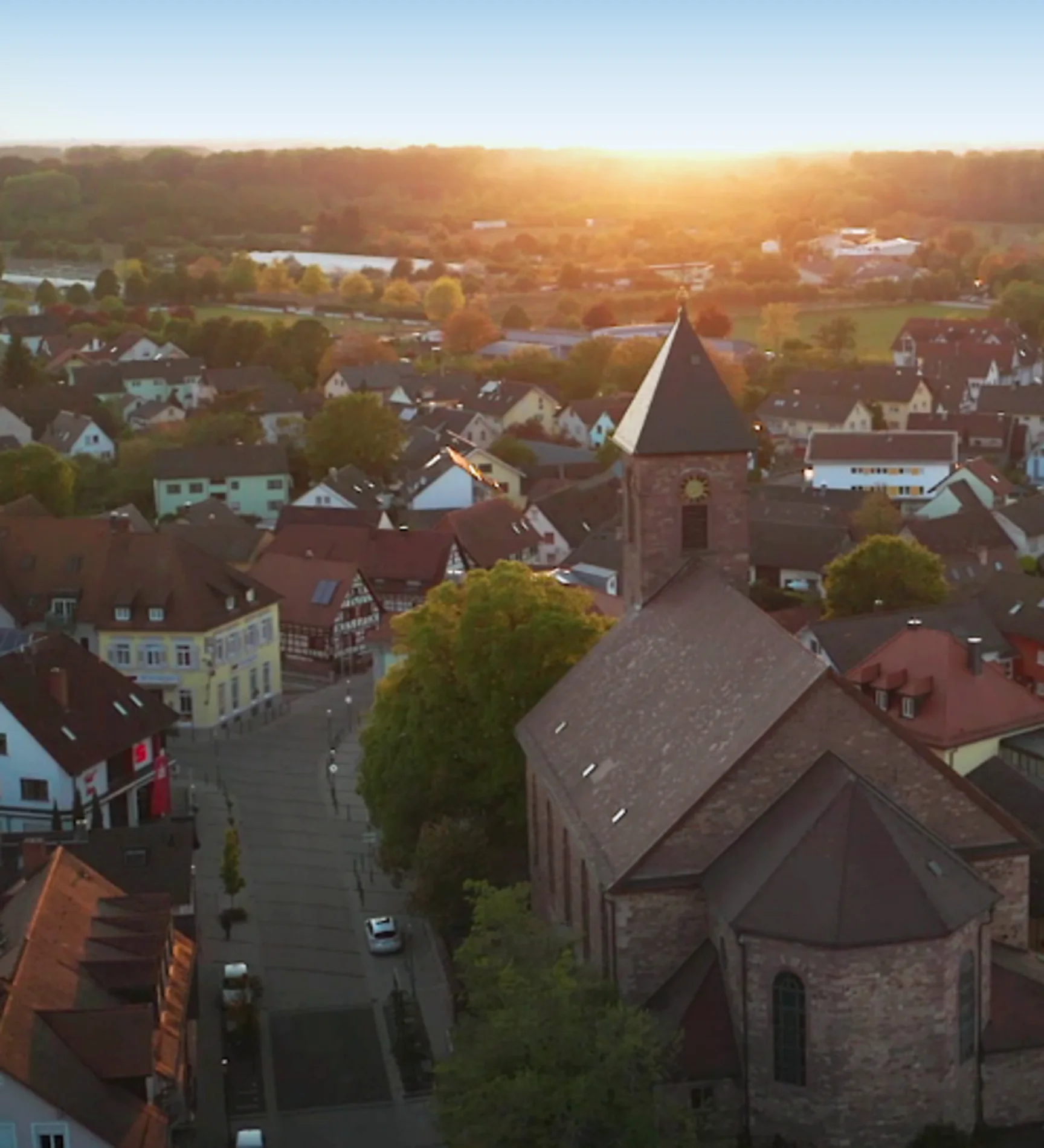 Luftaufnahme von Iffezheim bei Sonnenuntergang, die warmen Farben des Himmels spiegeln sich in den Gebäuden wider.